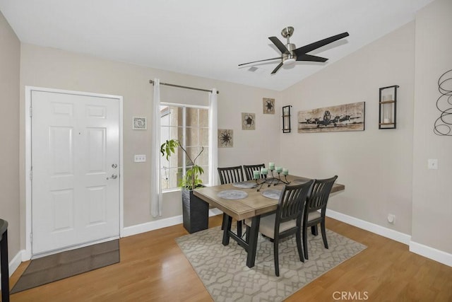 dining room with light wood-style flooring, baseboards, ceiling fan, and vaulted ceiling