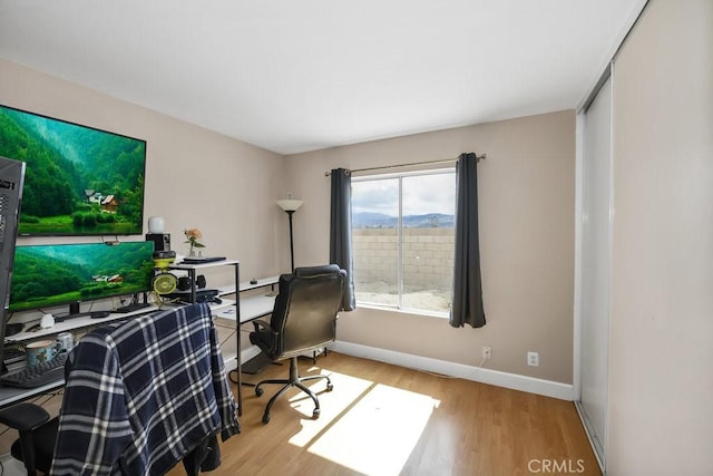 home office with a mountain view, baseboards, and wood finished floors