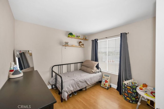 bedroom featuring light wood finished floors and baseboards