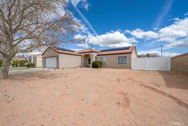 view of front of property featuring solar panels, fence, a tiled roof, stucco siding, and a garage