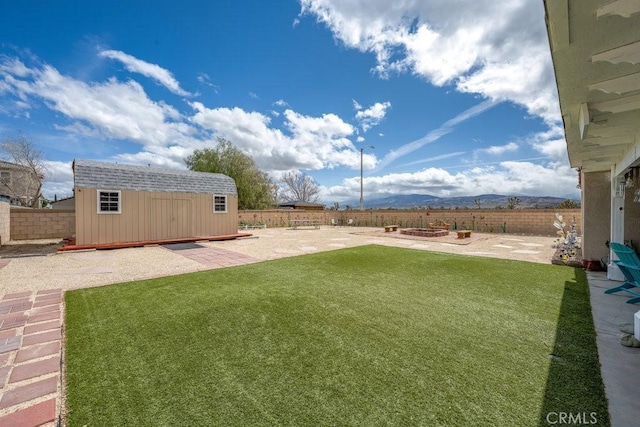 view of yard featuring a fenced backyard, an outbuilding, a mountain view, a storage unit, and a patio