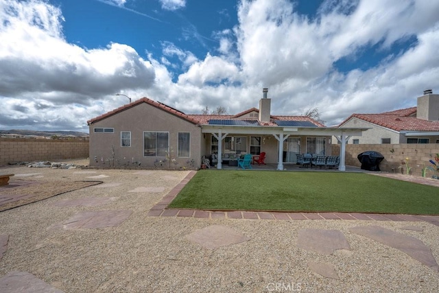 rear view of property featuring stucco siding, a tiled roof, a patio, and fence