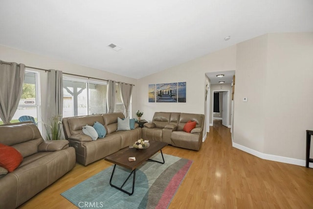 living area with vaulted ceiling, baseboards, light wood-type flooring, and visible vents