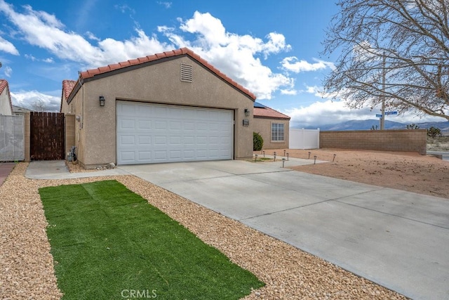 view of front of home featuring an attached garage, fence, a tile roof, stucco siding, and driveway