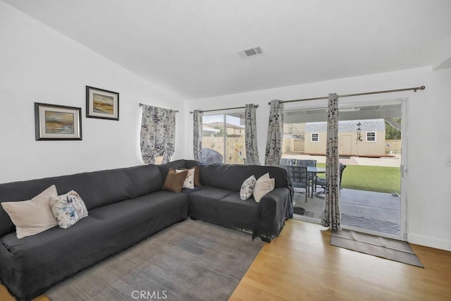 living room with visible vents, lofted ceiling, baseboards, and wood finished floors