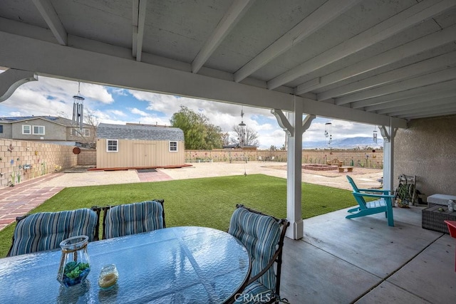 view of patio featuring a fenced backyard, a shed, outdoor dining area, and an outdoor structure