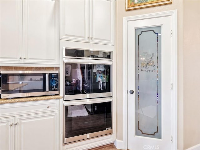 kitchen with appliances with stainless steel finishes, white cabinetry, and light countertops