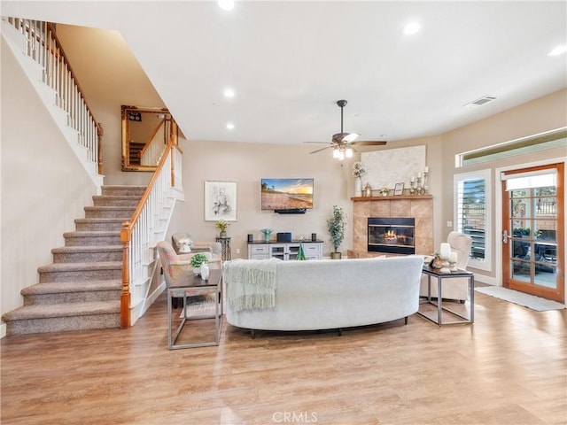 living area with light wood finished floors, recessed lighting, a fireplace, and stairs