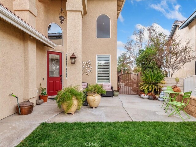 doorway to property with a patio, a gate, fence, and stucco siding