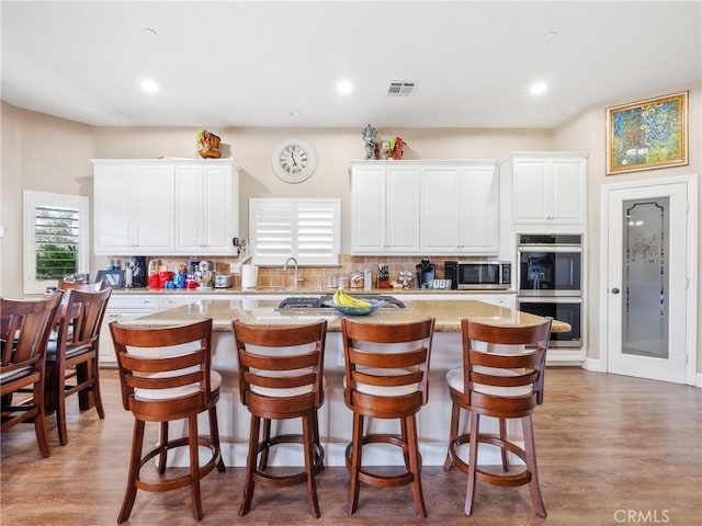 kitchen with visible vents, tasteful backsplash, white cabinets, and stainless steel appliances