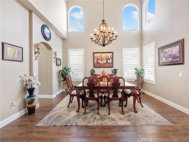 dining room with a healthy amount of sunlight, wood finished floors, and an inviting chandelier