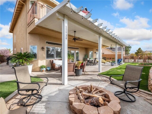 view of patio with ceiling fan, fence, and an outdoor fire pit