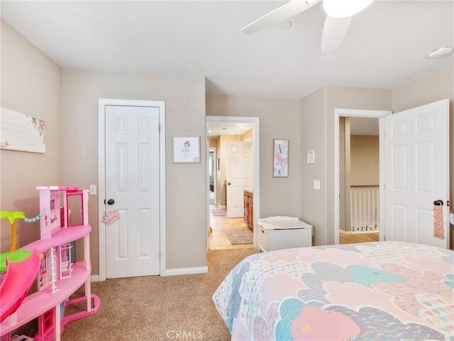 bedroom featuring light colored carpet, connected bathroom, baseboards, and ceiling fan