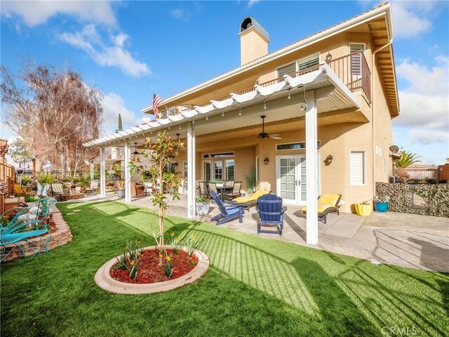 back of property featuring stucco siding, french doors, a yard, a balcony, and ceiling fan