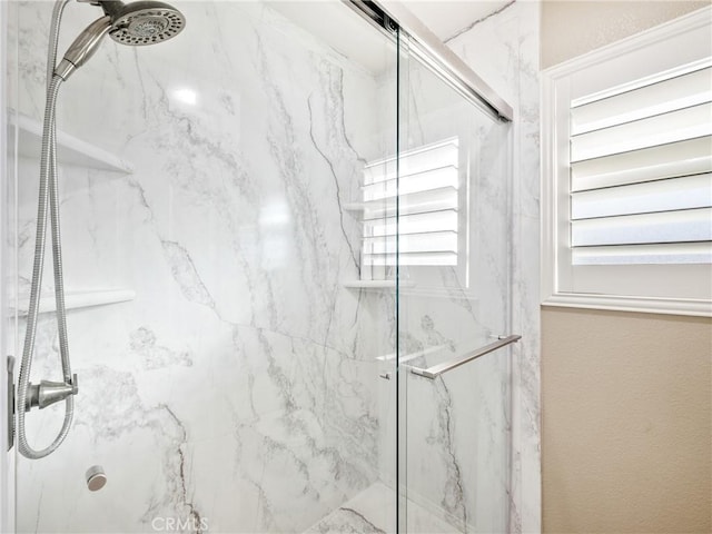 bathroom featuring a marble finish shower and a wealth of natural light