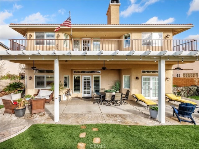 back of house featuring ceiling fan, french doors, a chimney, a balcony, and a patio