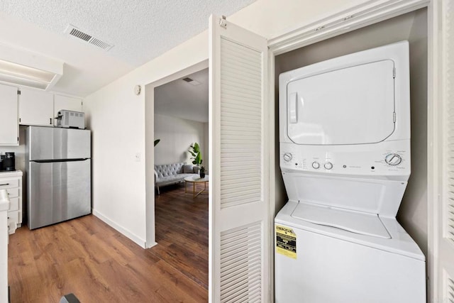 washroom featuring light wood-type flooring, visible vents, stacked washer and dryer, and laundry area