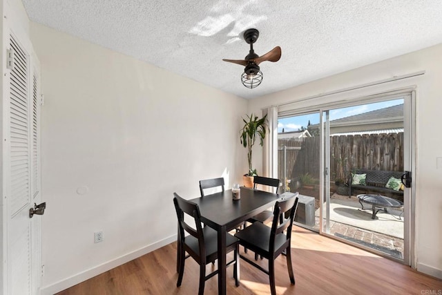 dining area featuring a textured ceiling, wood finished floors, baseboards, and ceiling fan