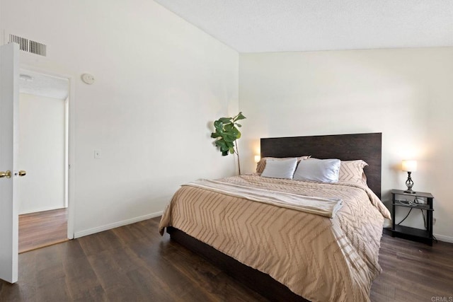 bedroom with visible vents, baseboards, and wood finished floors