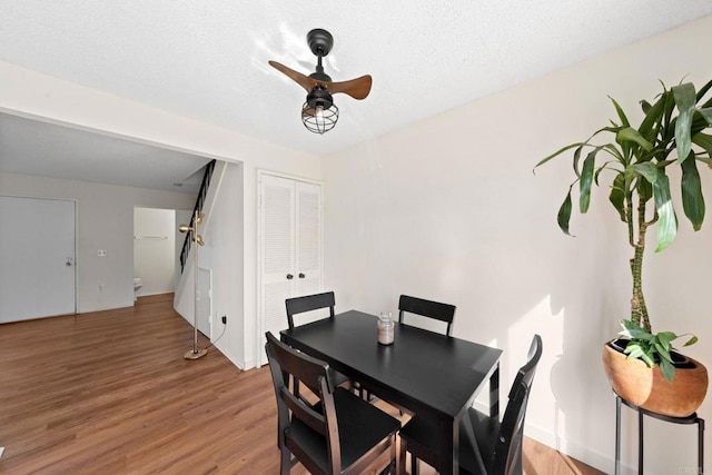 dining area with light wood finished floors, a textured ceiling, and a ceiling fan