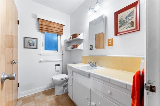 bathroom with baseboards, toilet, and vanity