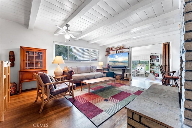 living area featuring beamed ceiling, wooden ceiling, wood finished floors, and a ceiling fan