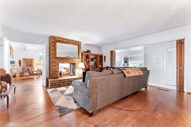 living room featuring a brick fireplace and wood finished floors