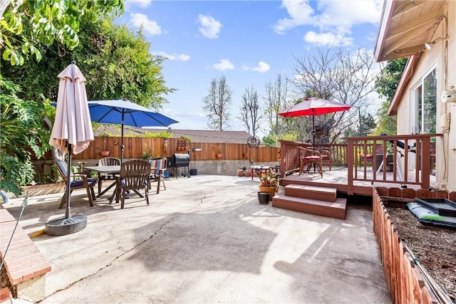 view of patio / terrace featuring outdoor dining space, a grill, a fenced backyard, and a deck