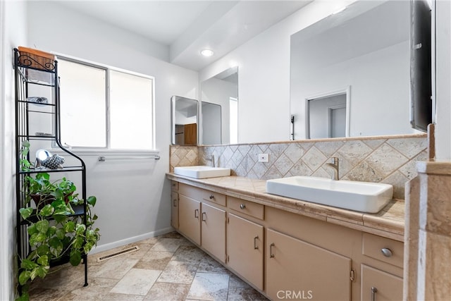 bathroom featuring double vanity, baseboards, backsplash, and a sink