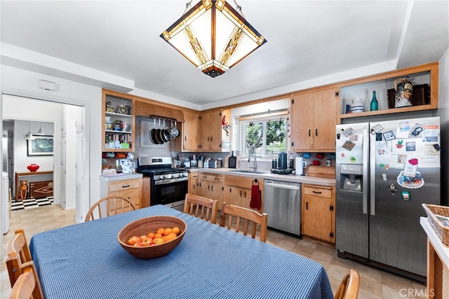 kitchen with a sink, appliances with stainless steel finishes, light countertops, and open shelves