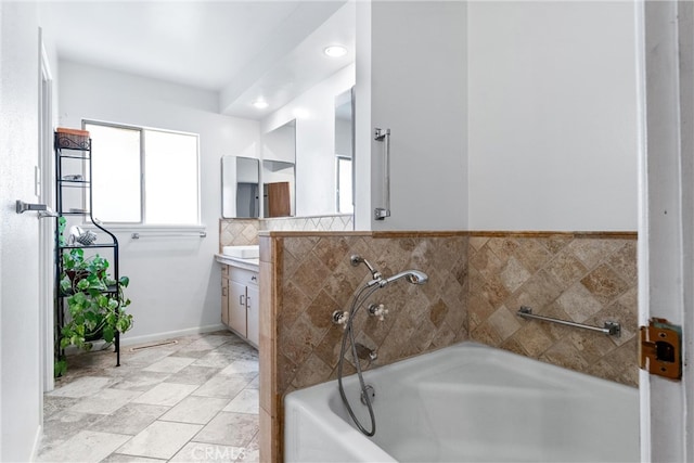 bathroom featuring vanity, a bath, and baseboards