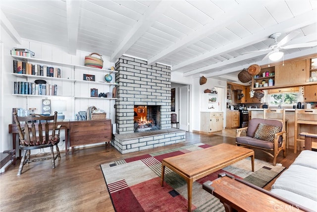 living area with baseboards, ceiling fan, beamed ceiling, a fireplace, and wood finished floors