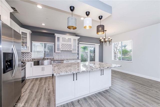 kitchen with decorative backsplash, white cabinets, appliances with stainless steel finishes, and a sink