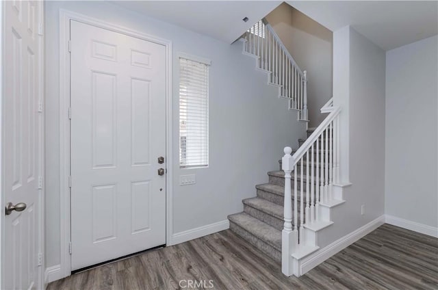 foyer entrance with baseboards, wood finished floors, and stairs