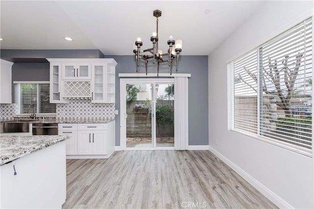 kitchen with a wealth of natural light, decorative backsplash, white cabinets, and stainless steel dishwasher