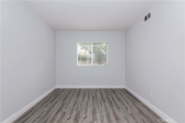 empty room with wood finished floors, baseboards, and visible vents