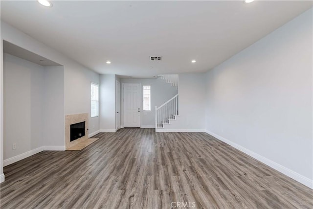 unfurnished living room with visible vents, baseboards, wood finished floors, and stairs