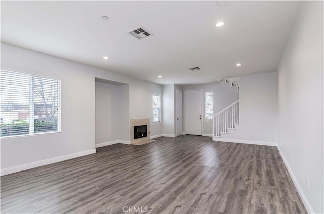 unfurnished living room with wood finished floors, visible vents, baseboards, recessed lighting, and stairs