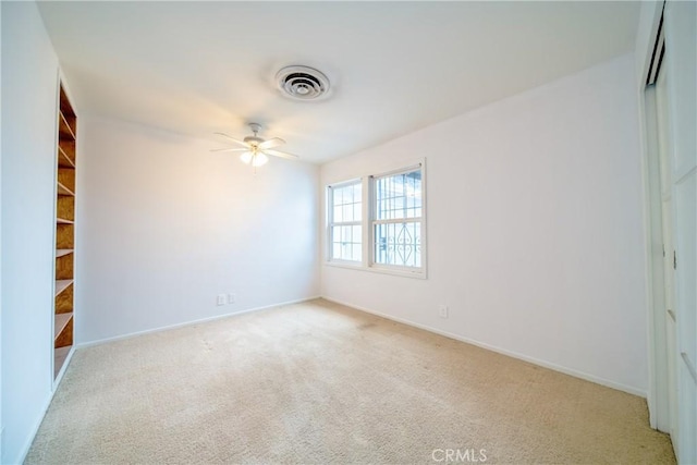 empty room featuring light carpet, visible vents, baseboards, and a ceiling fan