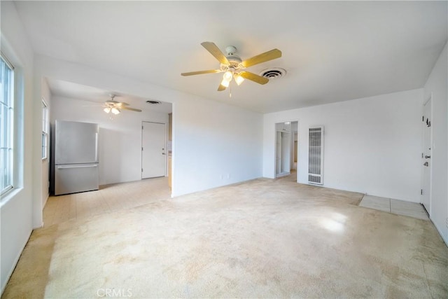 unfurnished living room with light carpet, visible vents, and a ceiling fan