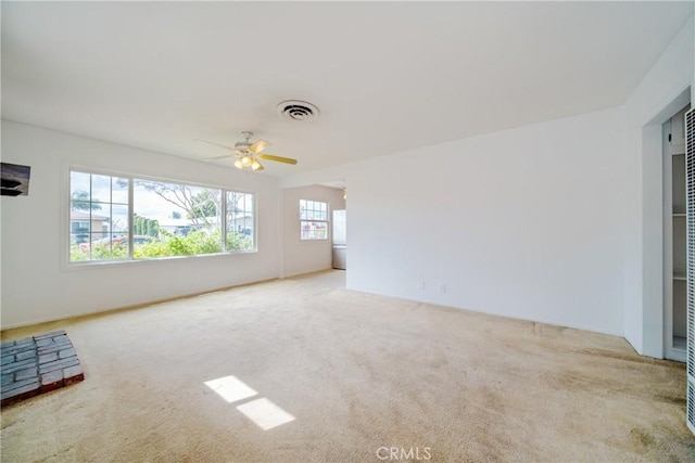 carpeted empty room featuring visible vents and ceiling fan