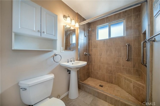 bathroom with tile patterned floors, tiled shower, and toilet