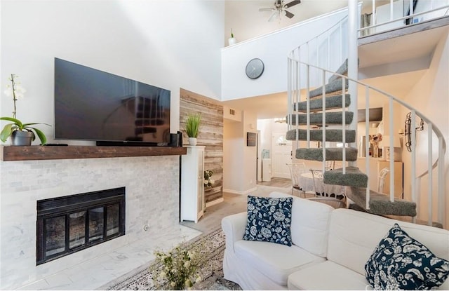 living room with a fireplace with flush hearth, baseboards, stairs, and a high ceiling