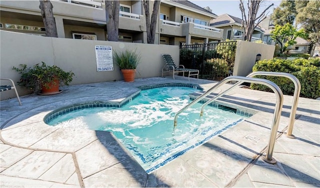 view of pool featuring a community hot tub, fence, and a residential view