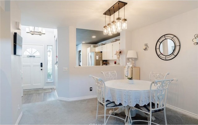 dining area with a notable chandelier, carpet, and baseboards