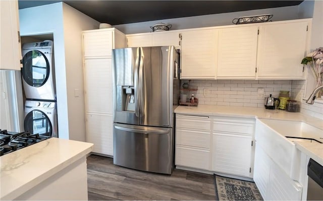 kitchen featuring dark wood finished floors, appliances with stainless steel finishes, white cabinetry, and stacked washer / drying machine