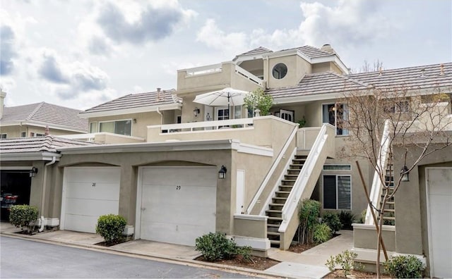 townhome / multi-family property with stucco siding, stairs, and a tiled roof