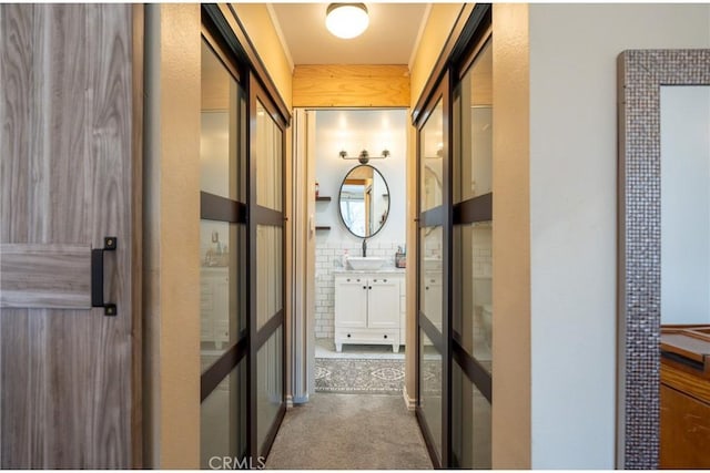 corridor featuring carpet flooring and a sink