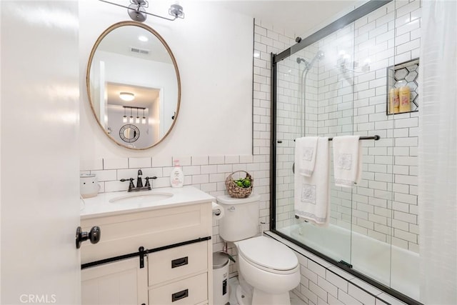 full bathroom featuring visible vents, tile walls, toilet, vanity, and tiled shower / bath