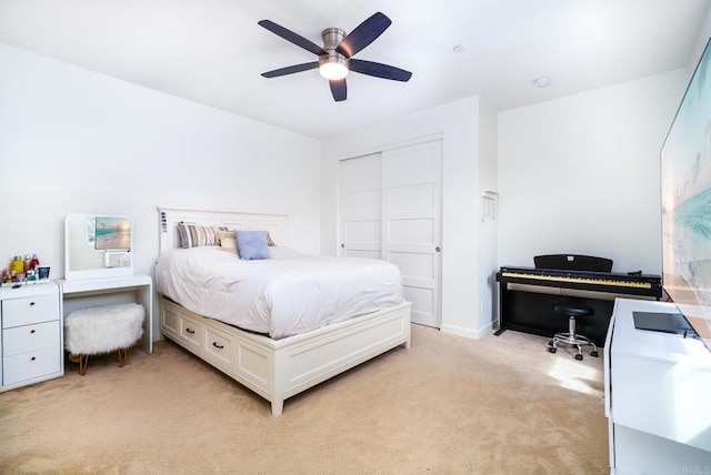 bedroom featuring a closet, baseboards, light colored carpet, and a ceiling fan